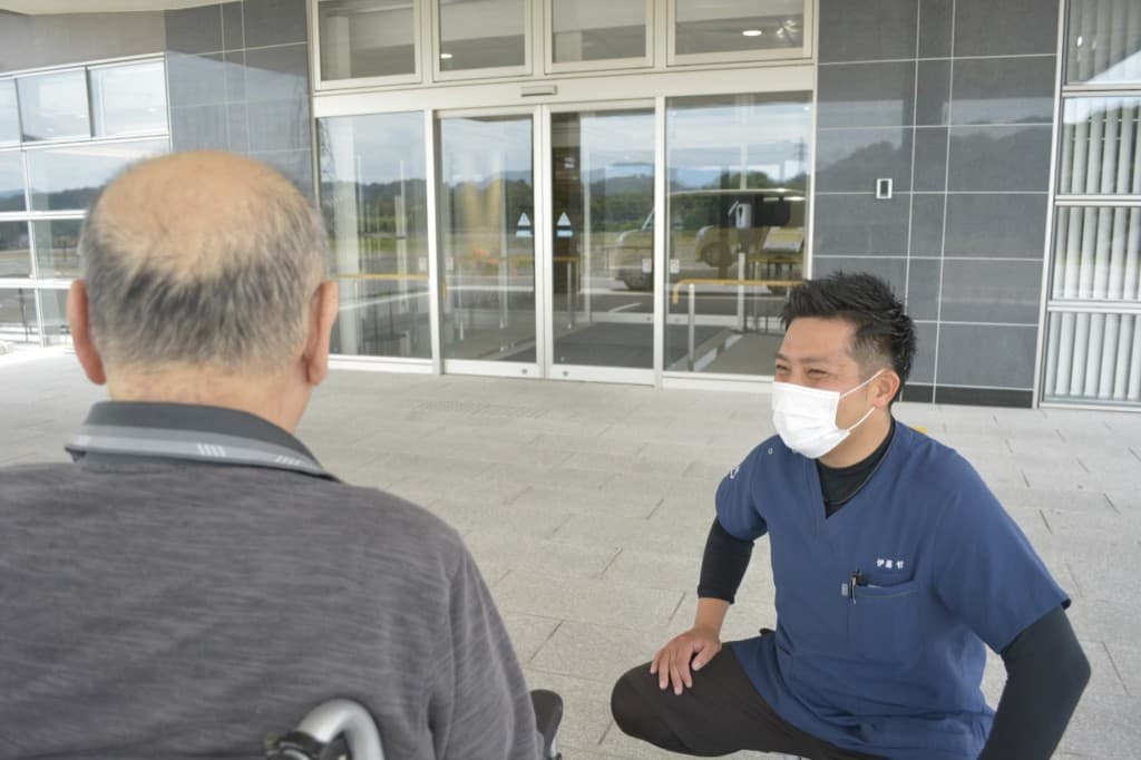 車椅子のご利用者様に目線を合わせて対話する専門職