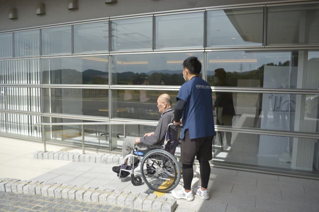 施設の入口で、車椅子のご利用者様を介助するWORKERS CAREの専門職